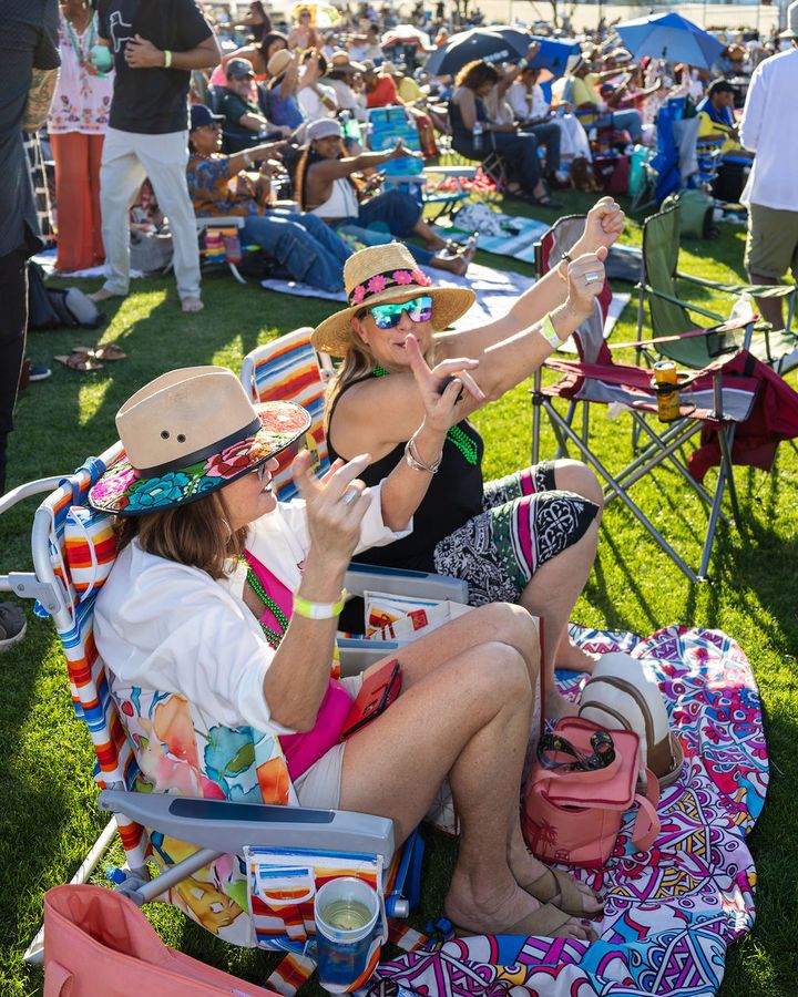 Three guests in hats laughing in their chairs
