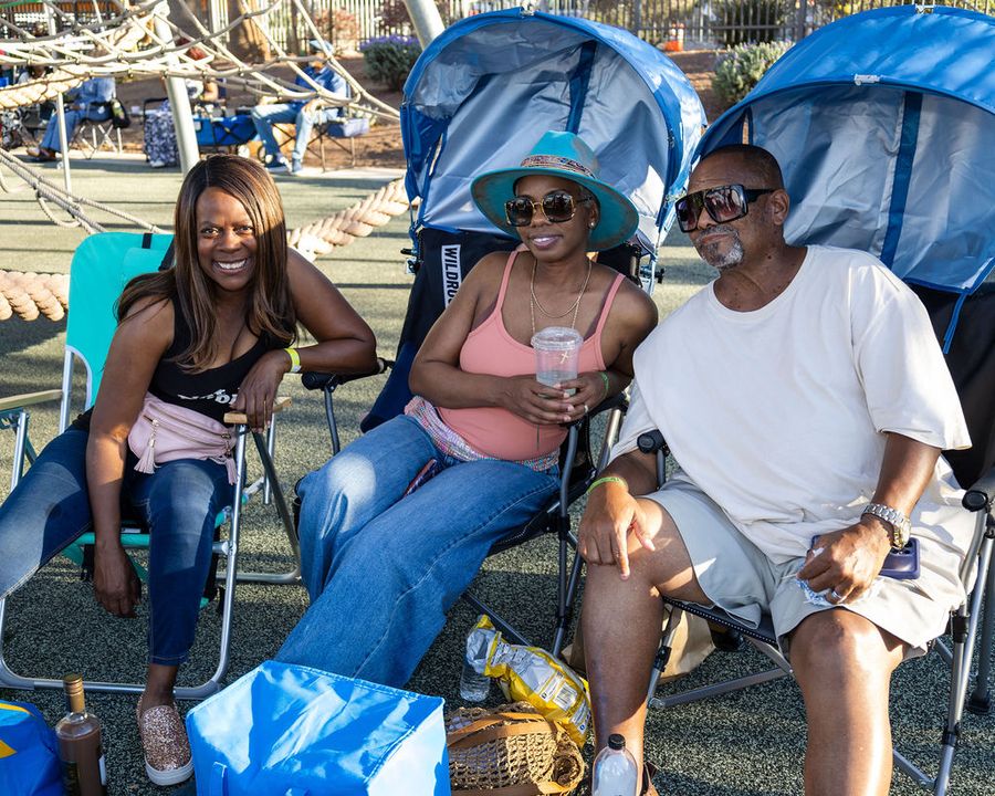Friends in chairs under a shade canopy