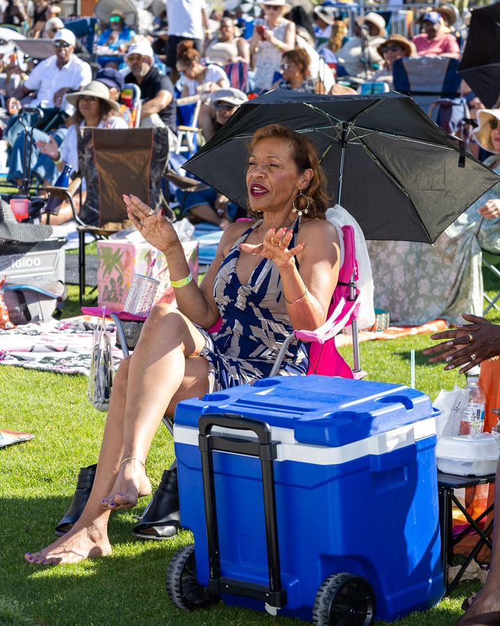 Guests sitting with a cooler between them on the grass