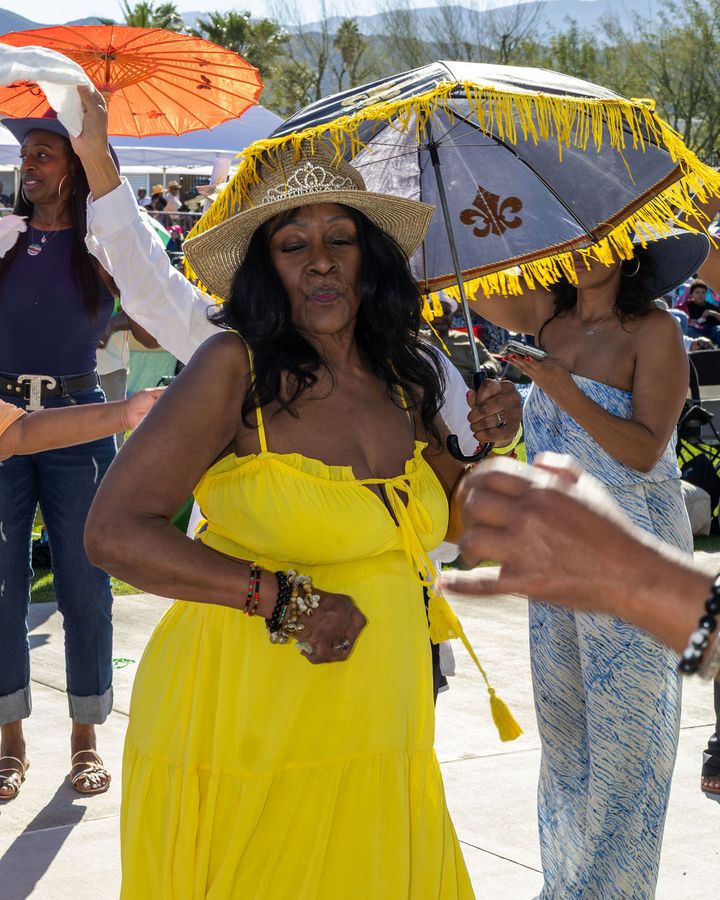 A guest in a yellow dress with a parasol