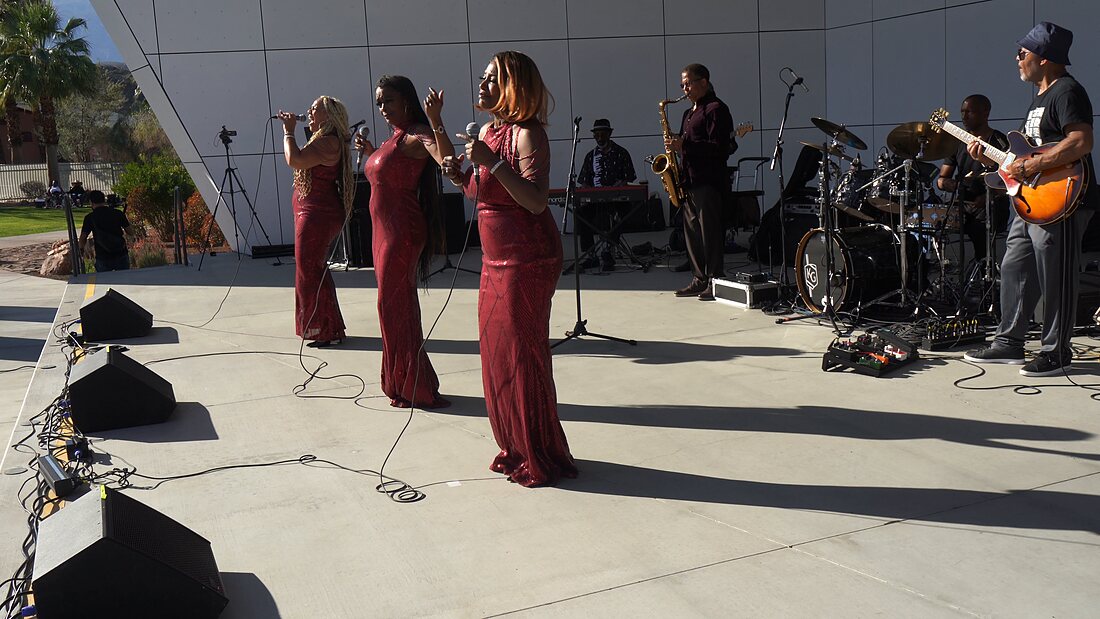 The vocal trio and full band performing on the amphitheater stage