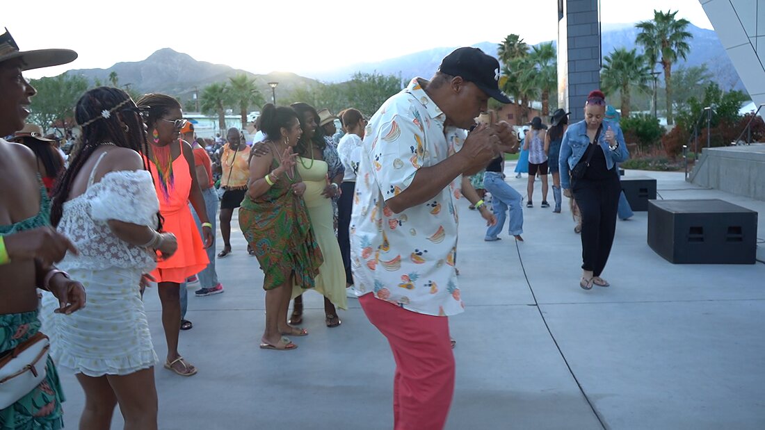 Guests line dancing on the walkway with the mountains behind them