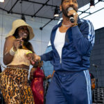 Performer singing on stage with a fan dancing beside him at Soul Springs Festival
