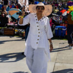 Woman in white outfit and sun hat with a fan at Soul Springs Festival