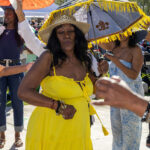 Woman dancing in a yellow dress under colorful parasols at Soul Springs Festival